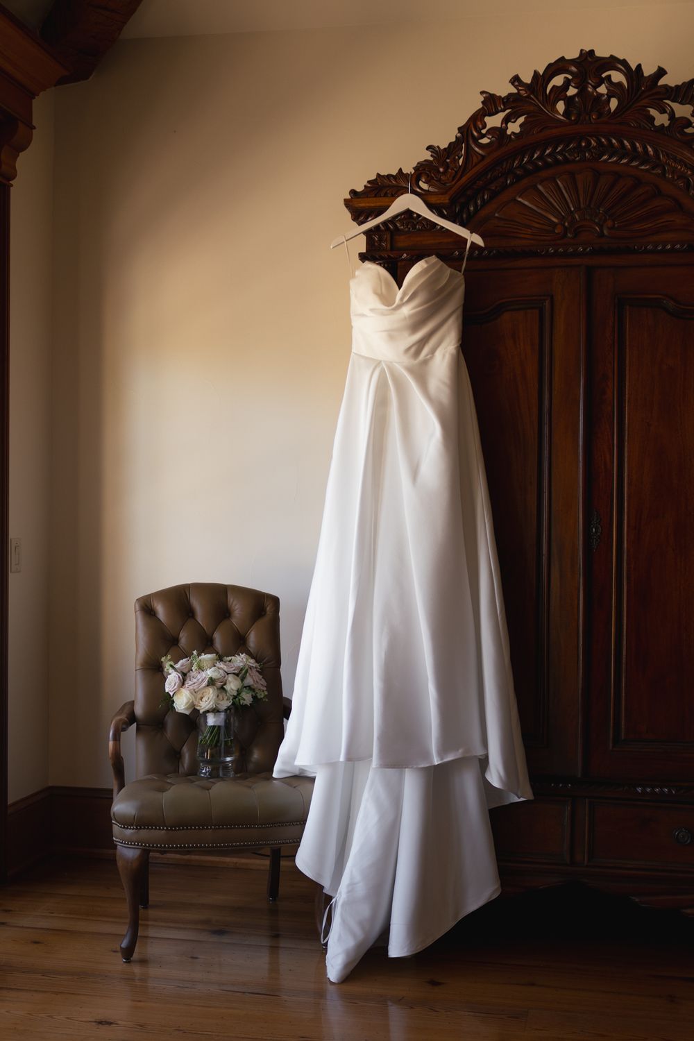 A white wedding dress hangs elegantly against dark wooden furniture in a series of artistic detail shots.
