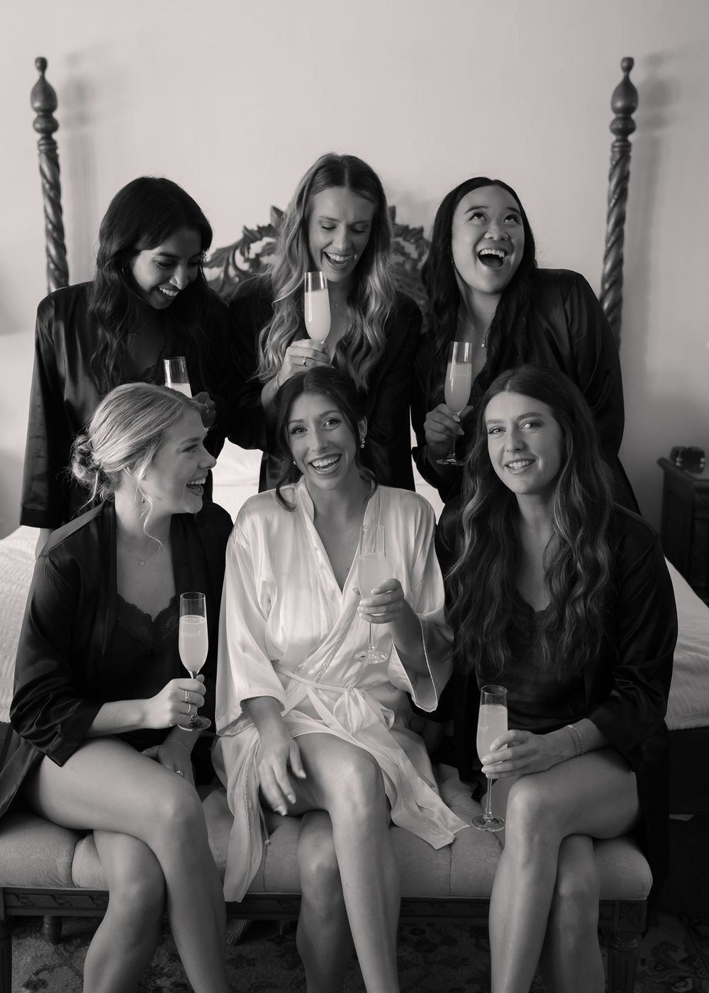 A group of friends in black and white robes sitting together on a couch in a casual setting.
