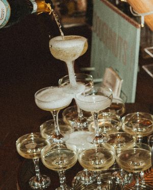 Champagne being poured into a tower of coupe glasses creating an elegant cascade effect at a celebratory event.