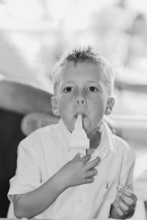 A child in a white shirt makes a quiet shushing gesture with their finger pressed to their lips.