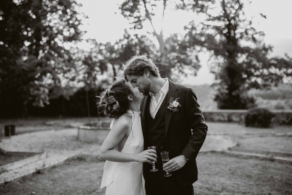 A romantic black and white wedding photo capturing a tender moment between newlyweds in an outdoor garden setting.