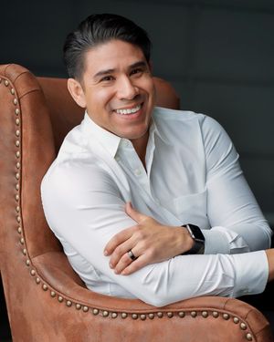 Person in white shirt relaxing in brown leather armchair.
