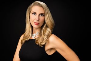 Elegant studio portrait of woman in black sleeveless top with statement necklace.