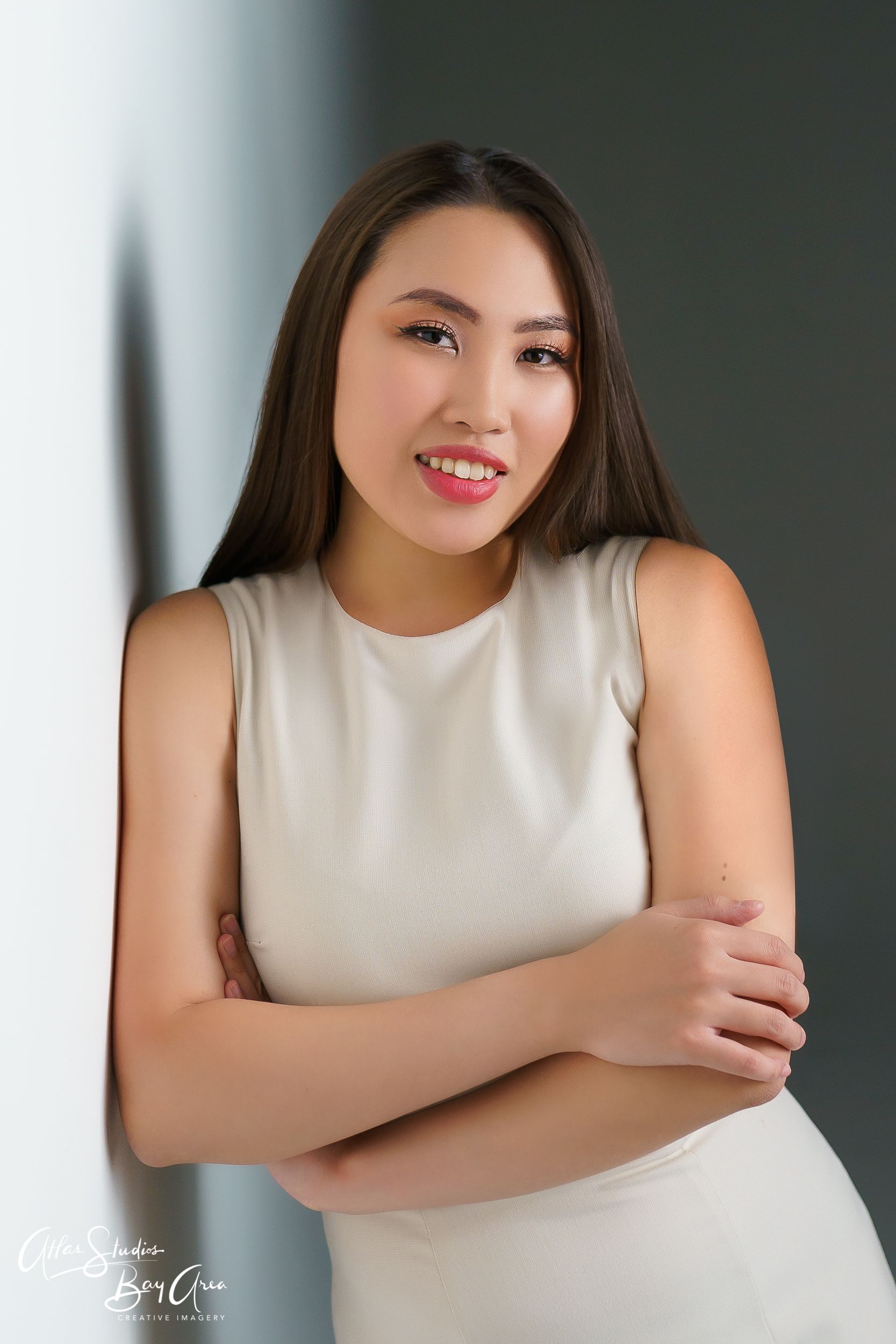 Studio portrait of a woman in a white sleeveless top with natural lighting and soft background.