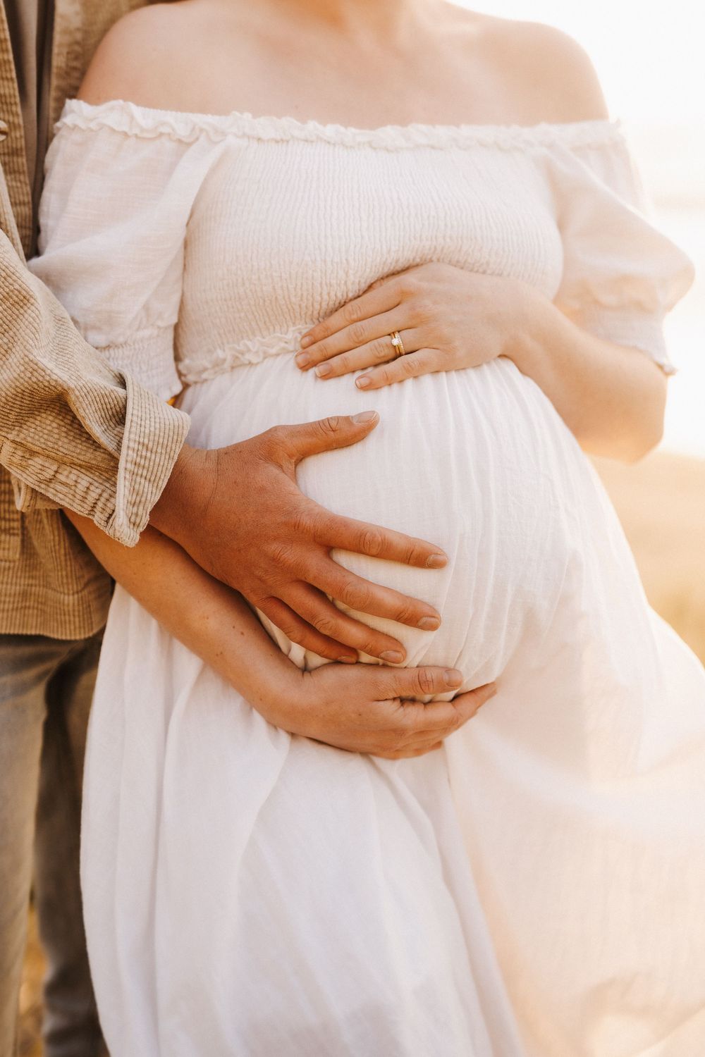 Heartfelt pregnancy progression photos showing hands cradling a growing baby bump in a white dress against warm lighting.