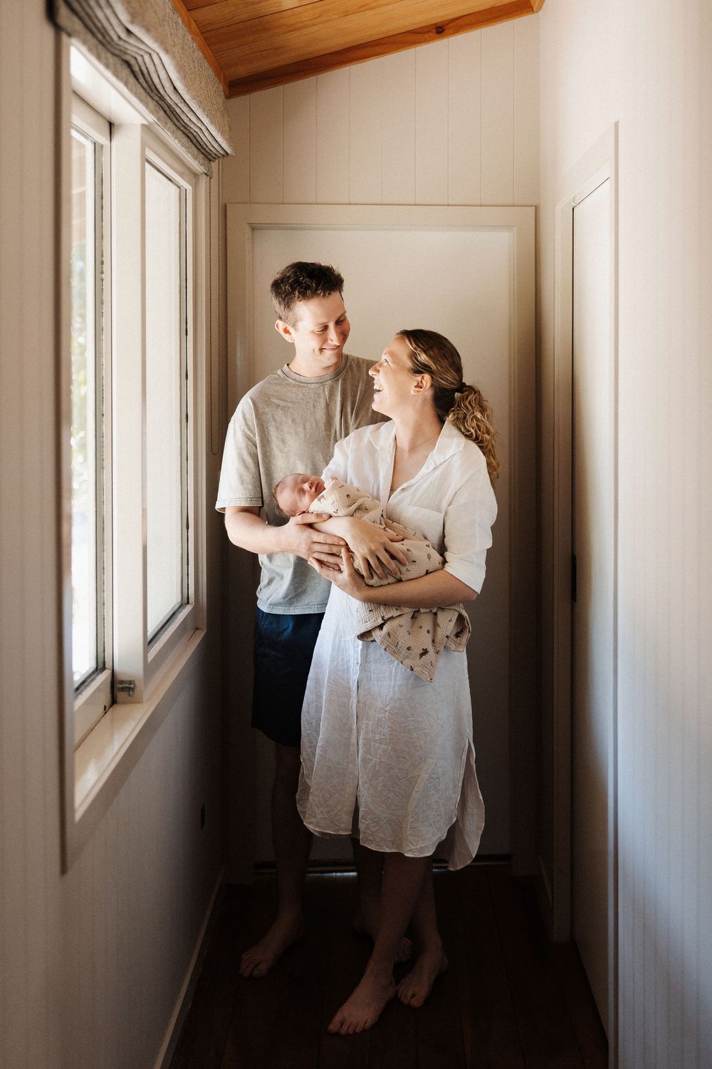 Parent walks tenderly along a sunlit hallway while holding an infant, with multiple poses showing nurturing moments.