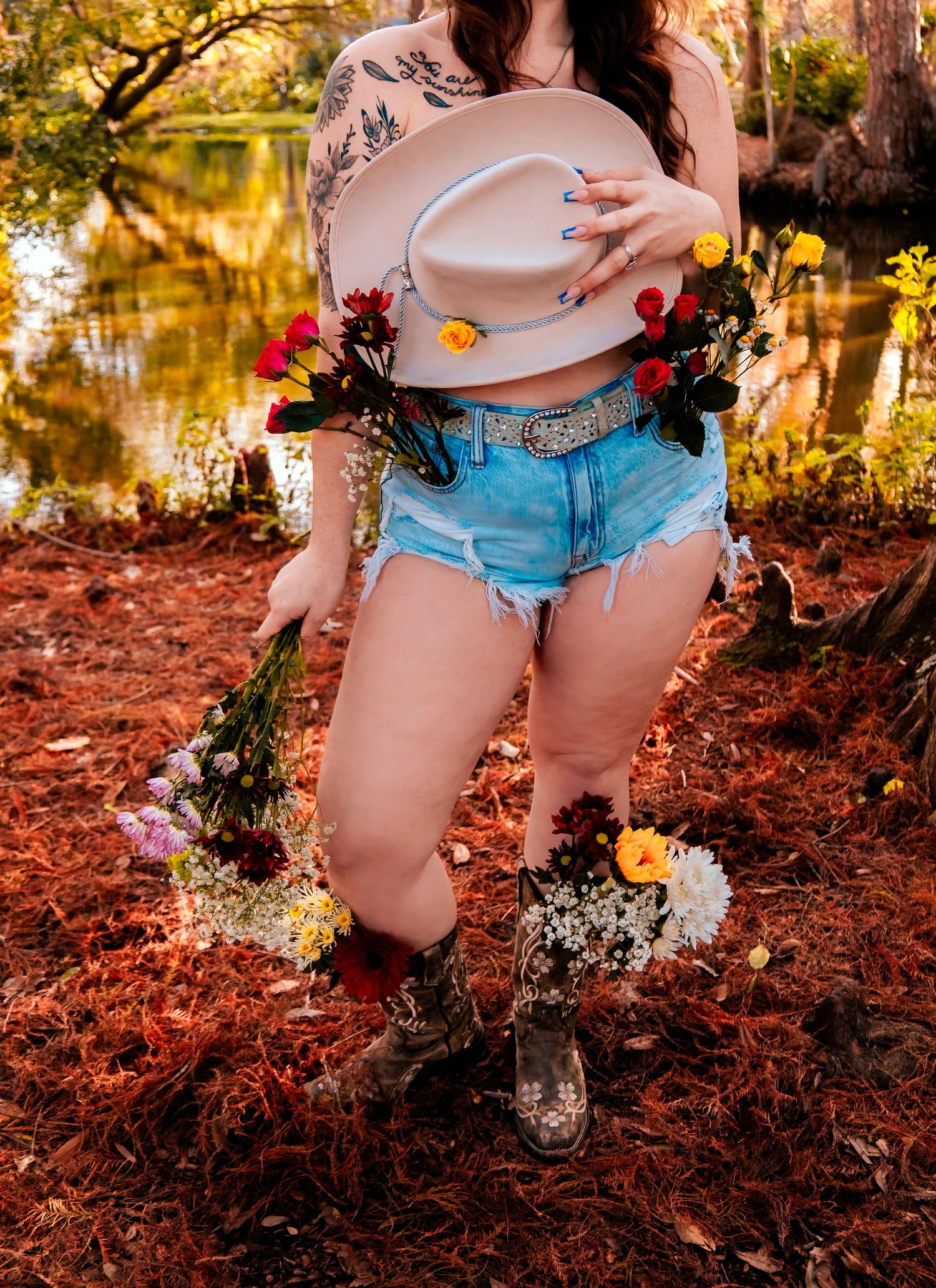 Rustic outdoor scene with cowboy hat and floral decorations near water.