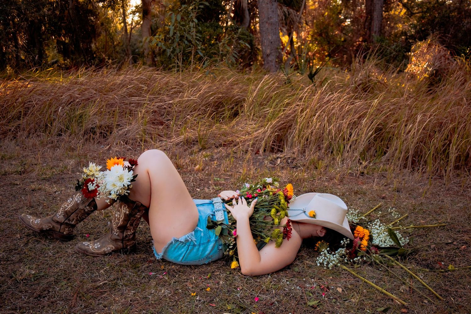 Artistic outdoor photo setup with flowers and props on rustic ground.
