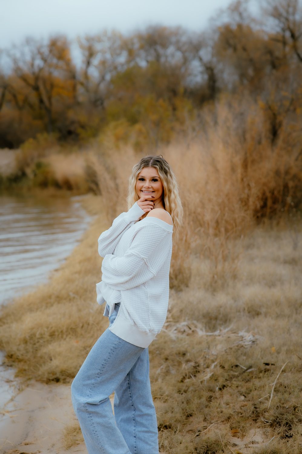 Natural light portrait of senior girl smiling in layered fall outfit by Enid OK photographer.