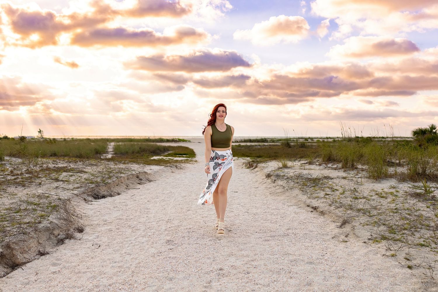Woman in white dress dancing on sandy path at golden hour.