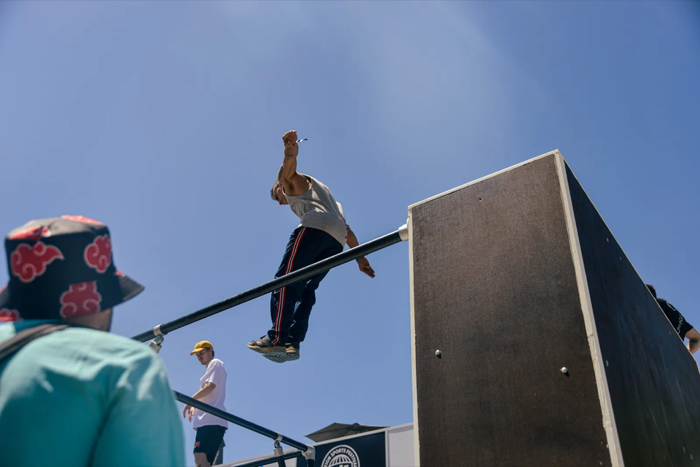 Athlète réalisant un saut spectaculaire depuis une rampe verticale, entouré de spectateurs.