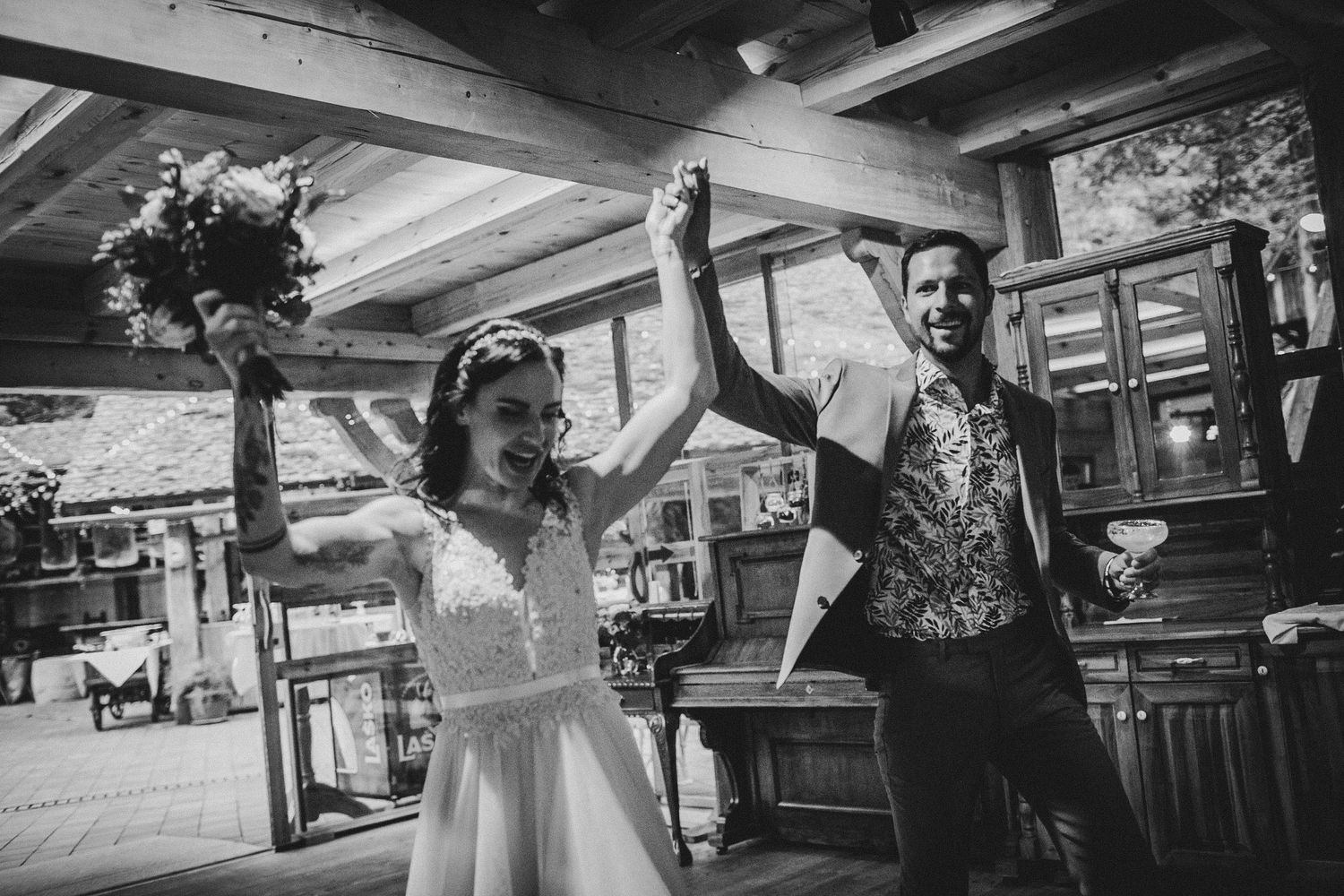 Black and white photo of celebratory moment at rustic indoor wedding reception.