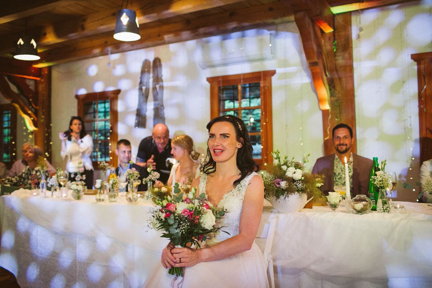 Wedding reception setup in rustic venue with decorated head table and ambient lighting.