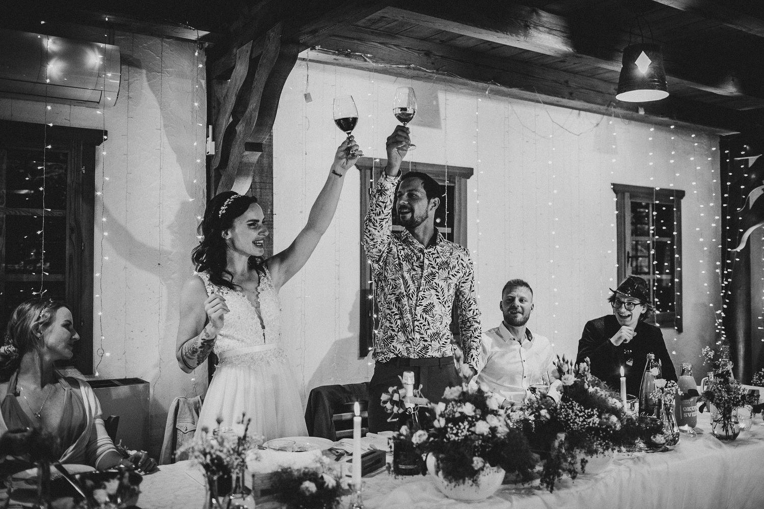 Wedding guests raise glasses for a celebratory toast at a festive reception dinner.