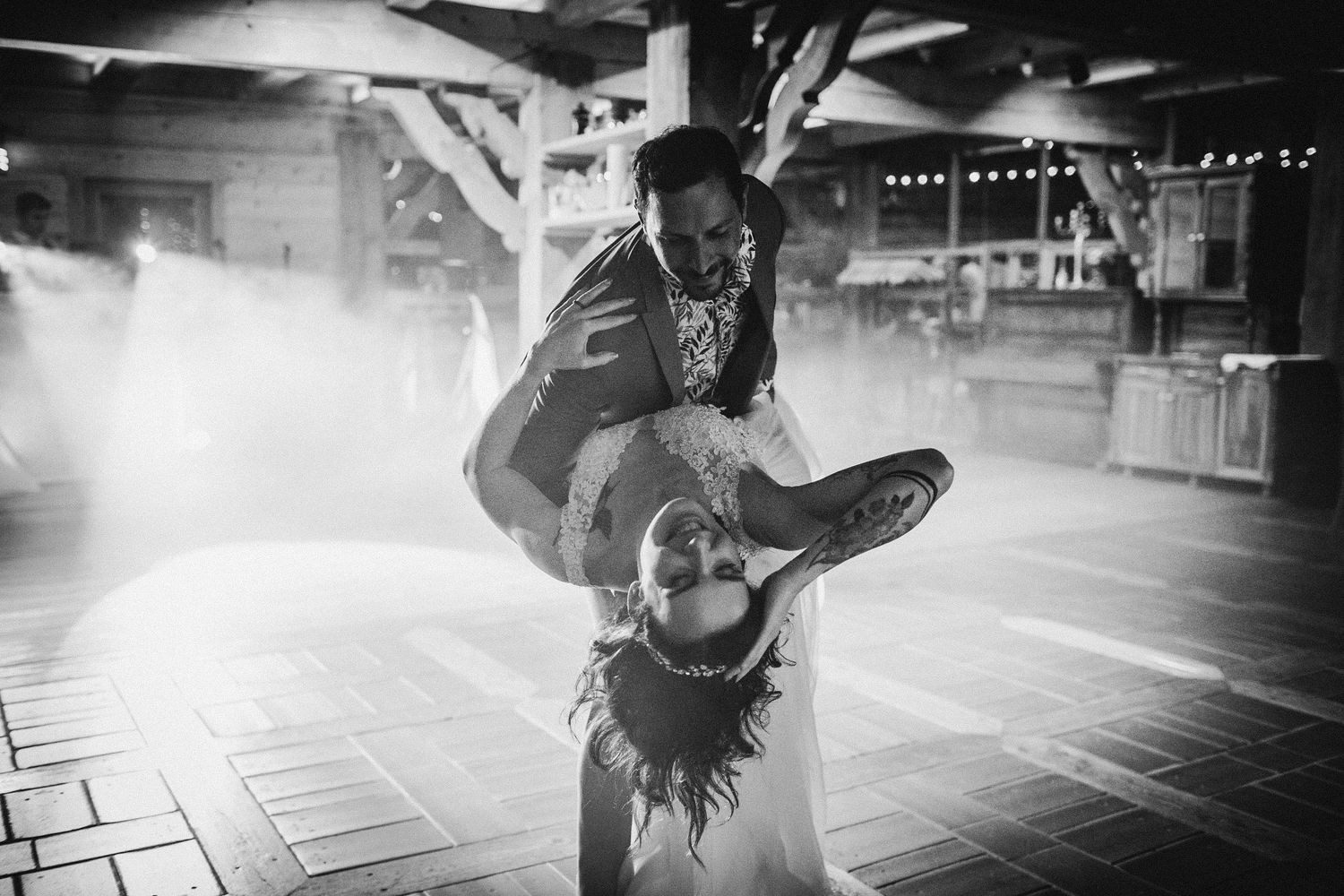 Dynamic dance move captured during a wedding reception with dramatic lighting effects.