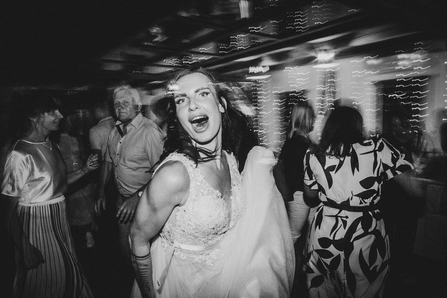 Black and white shot of enthusiastic dancing during lively wedding reception.