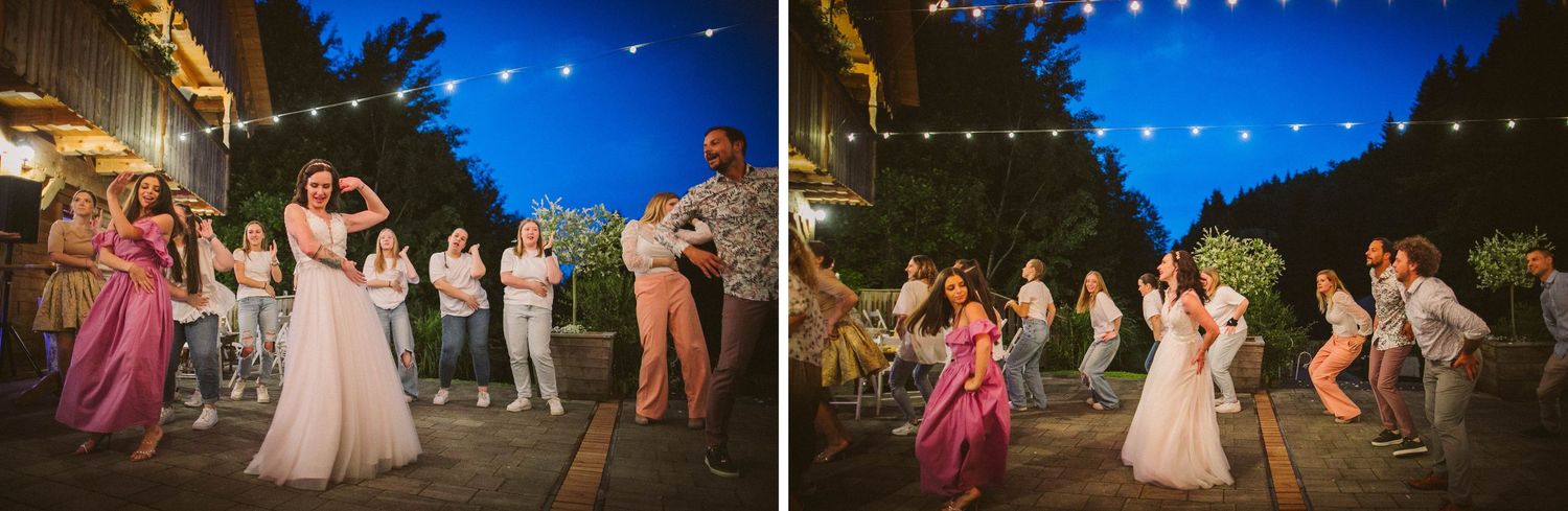 Wedding guests dance under twinkling string lights at an outdoor evening reception celebration.