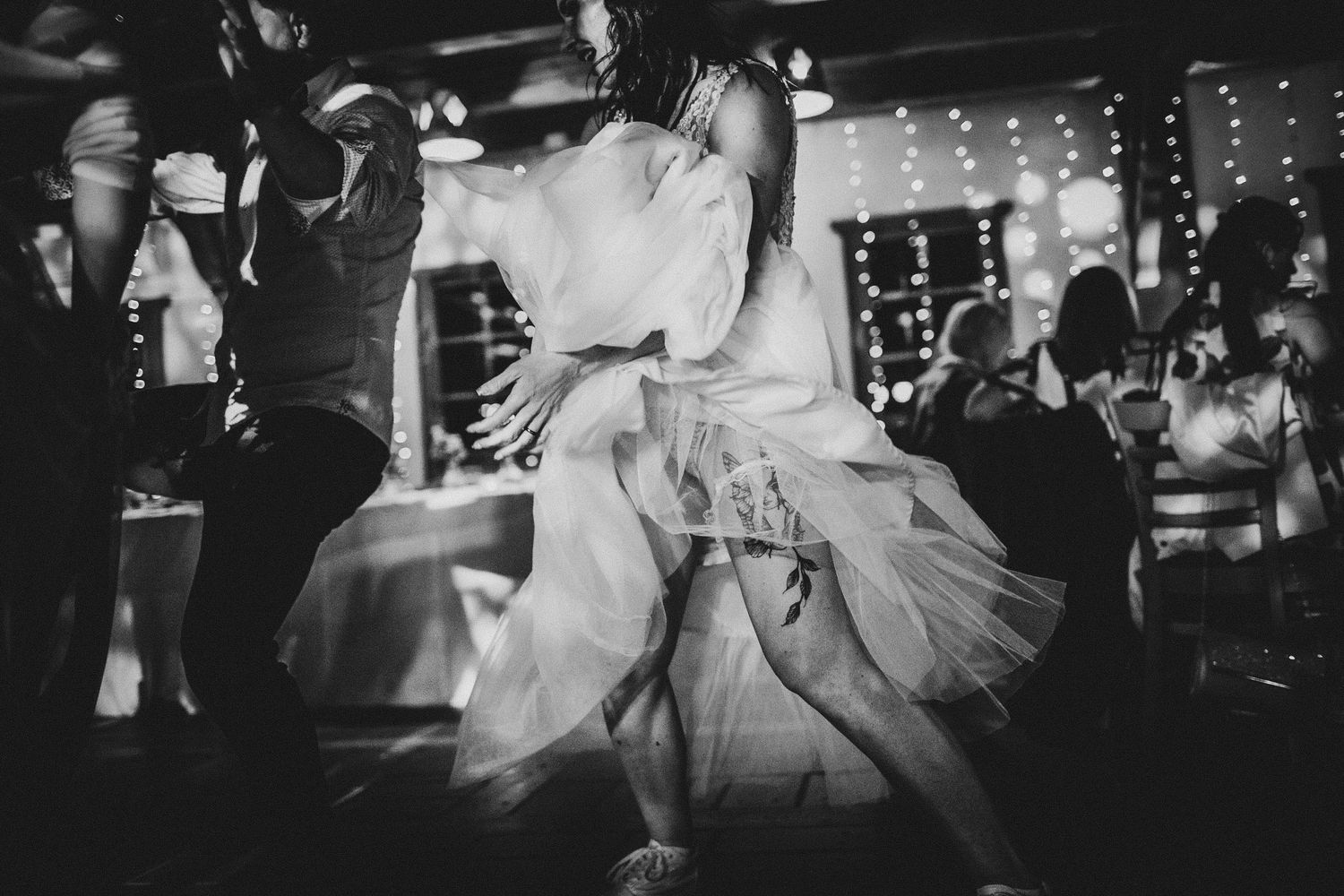 Black and white photo captures a twirling dress during an intimate wedding dance moment.