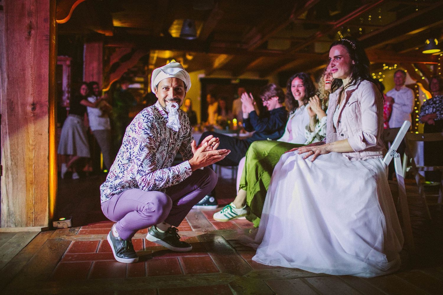 Two people share a fun moment on a dance floor during a wedding celebration at a rustic venue with wooden beams.