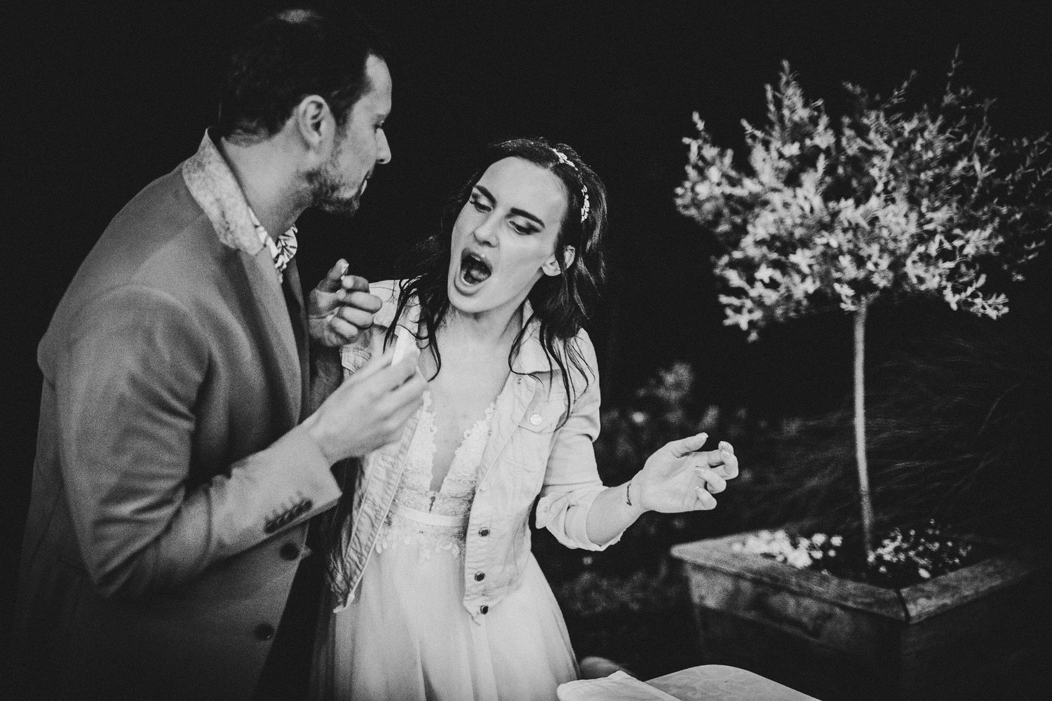 A dramatic black and white candid moment between a couple during their evening wedding celebration.