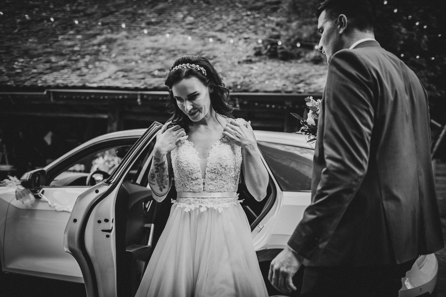 Black and white image showing an elegant dress detail as someone exits a car.