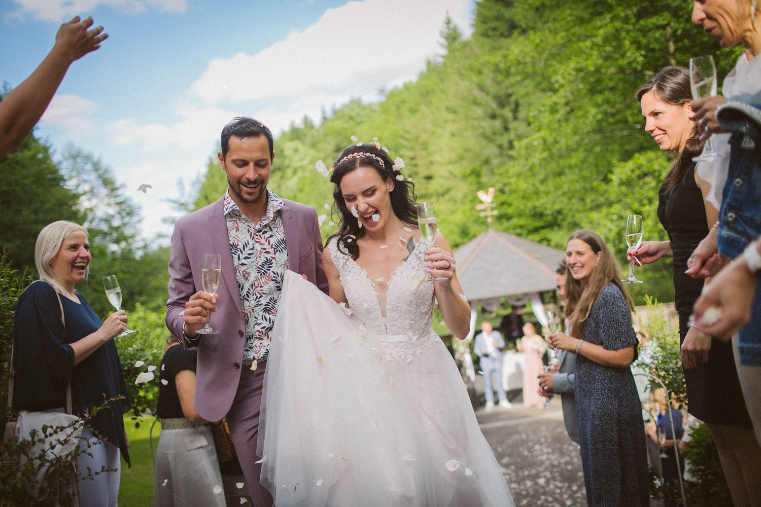 A joyful outdoor wedding celebration with people cheering and celebrating in a natural garden setting.