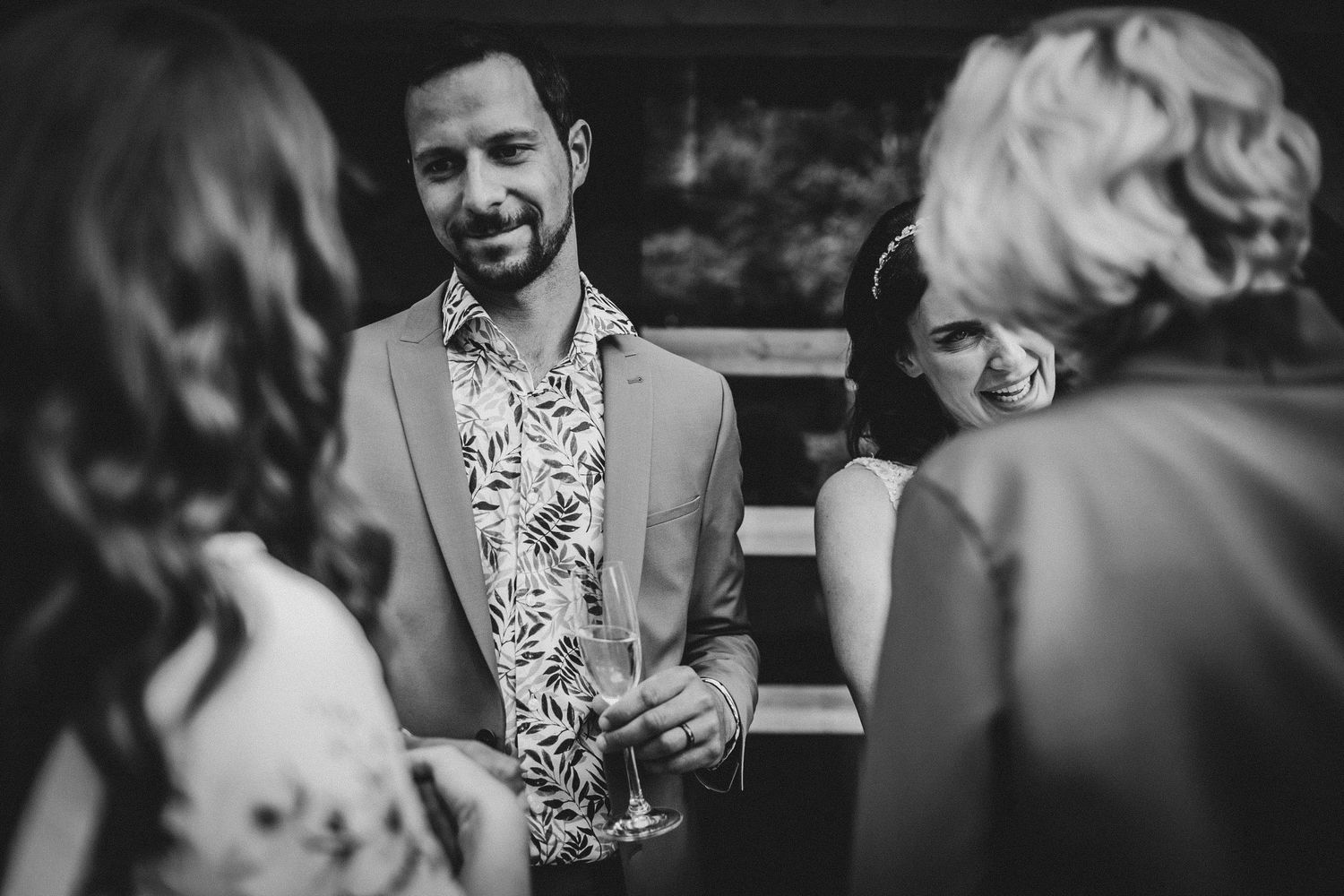 Black and white photo of guests engaged in conversation at outdoor party.