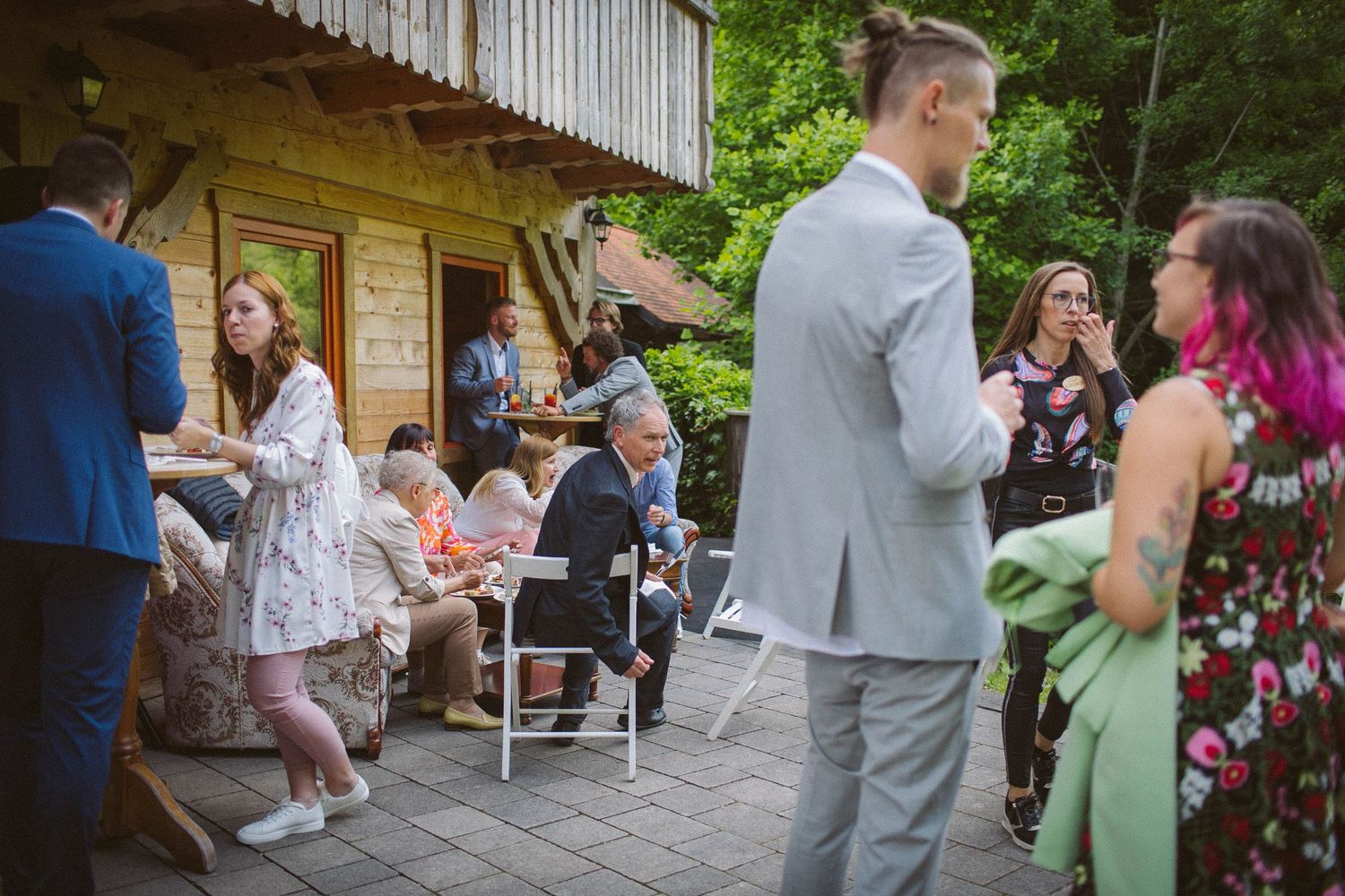 Guests mingle and socialize on a rustic wooden deck during an outdoor celebration.