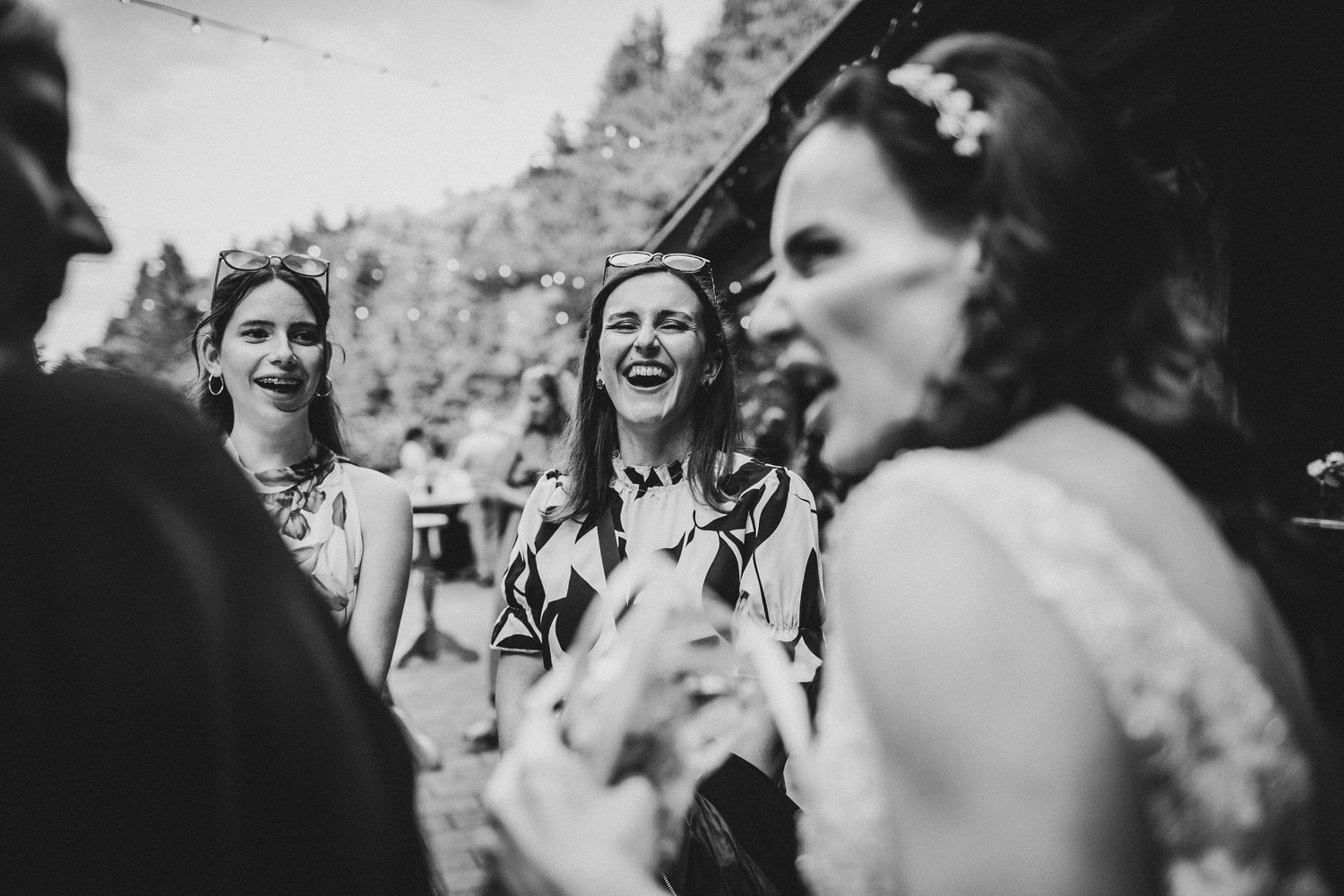 Black and white photo of guests laughing together at an outdoor party.
