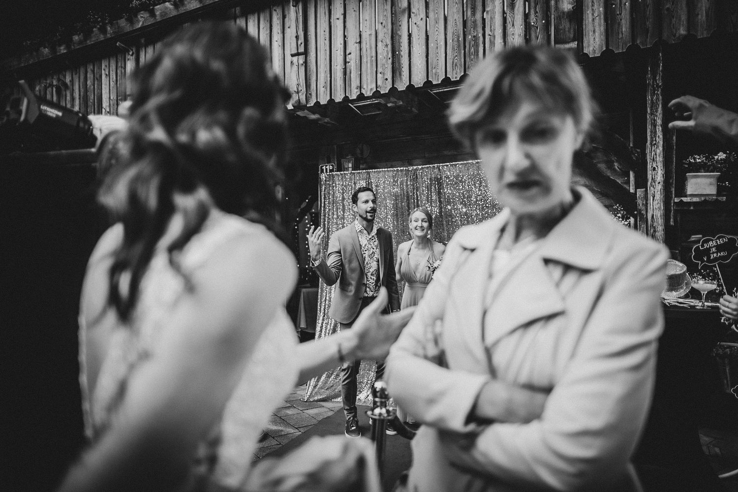 Black and white candid shot of guests conversing at a rustic venue.
