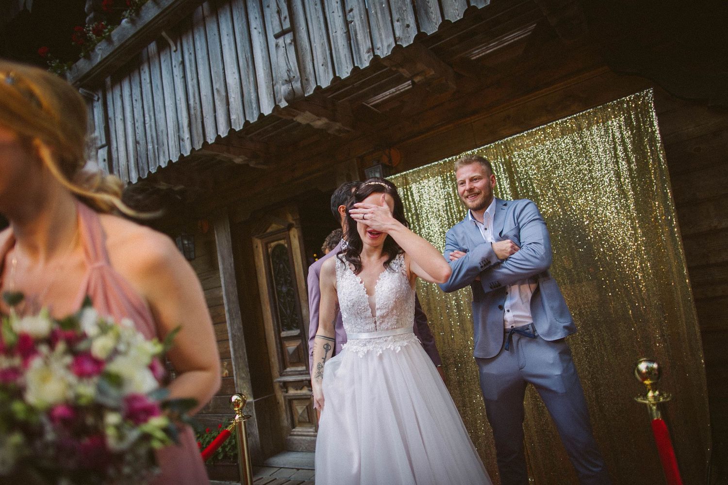 Emotional moment between wedding couple in front of sparkling gold backdrop.