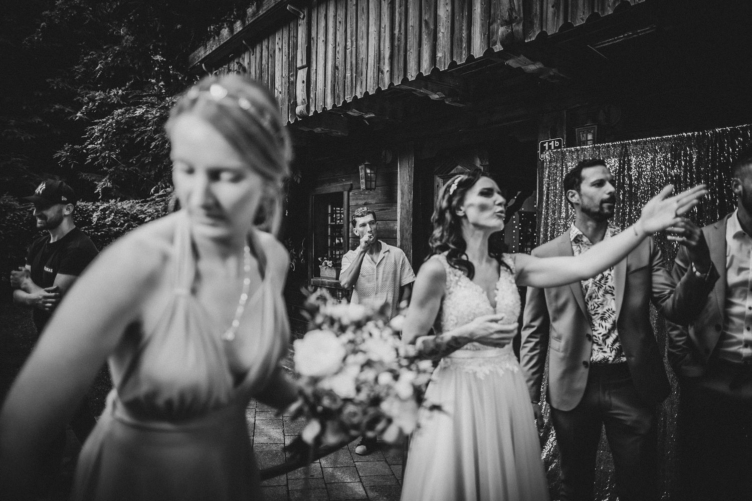 Candid black and white shot of wedding party celebrating outdoors.
