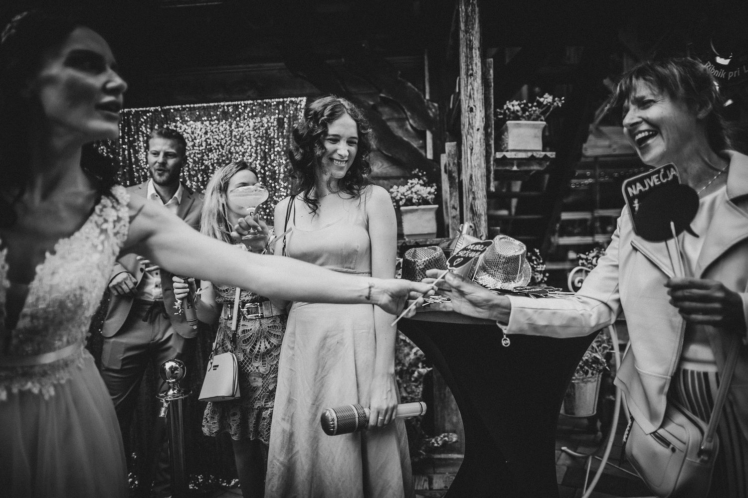 Black and white photo of wedding guests sharing drinks and laughter.