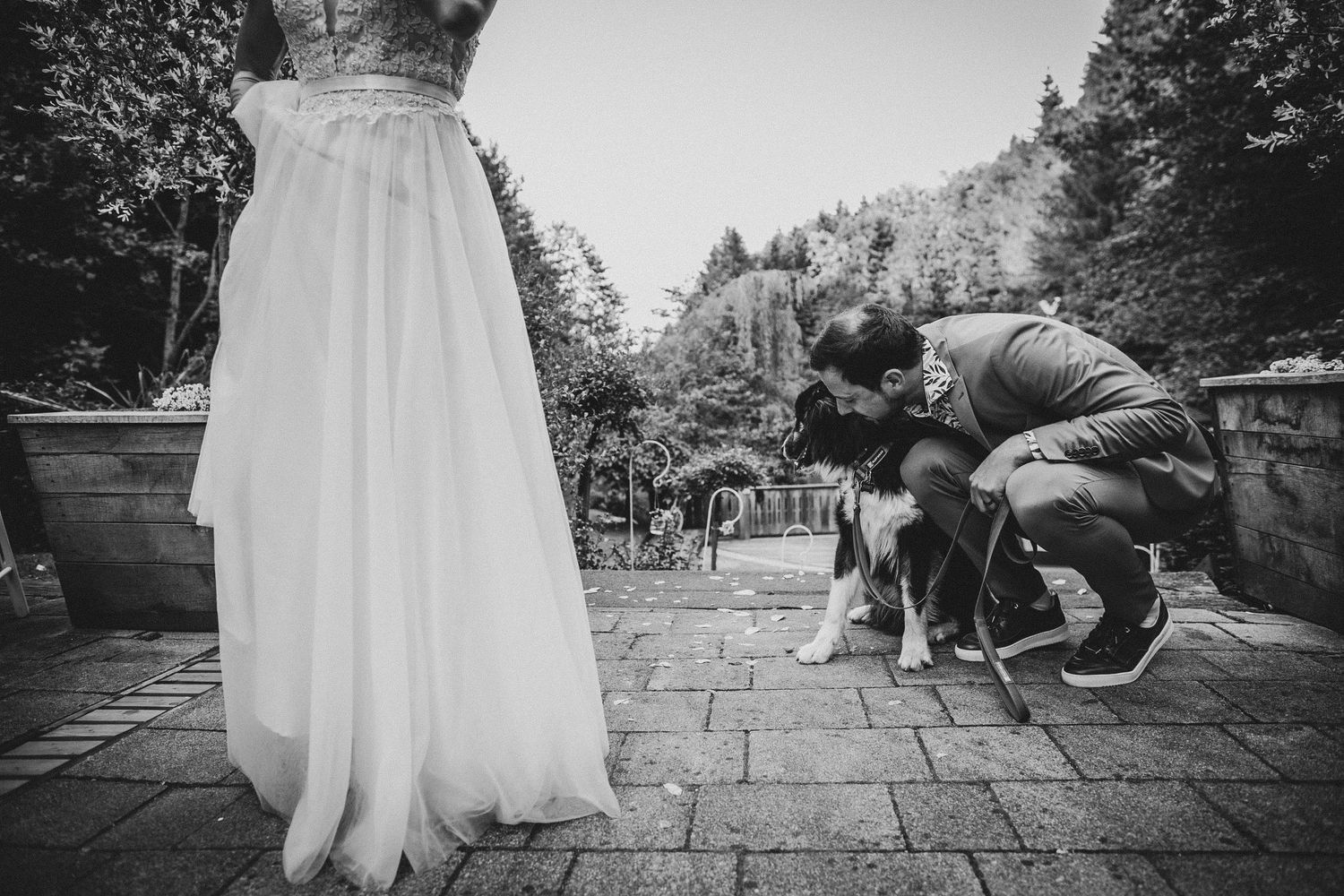 Black and white photo of a wedding dress with people kneeling outdoors on stone pavement.