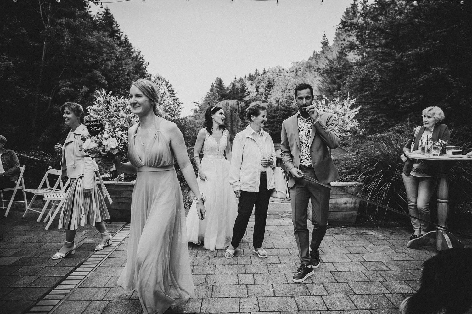 Wedding party members dancing and celebrating on an outdoor patio.