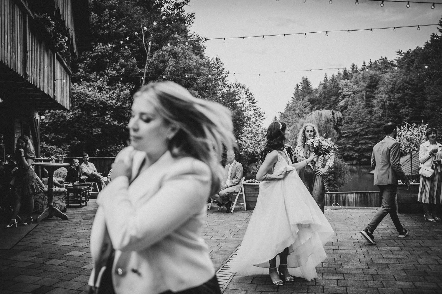 Wedding guests dance on an outdoor patio with string lights overhead.
