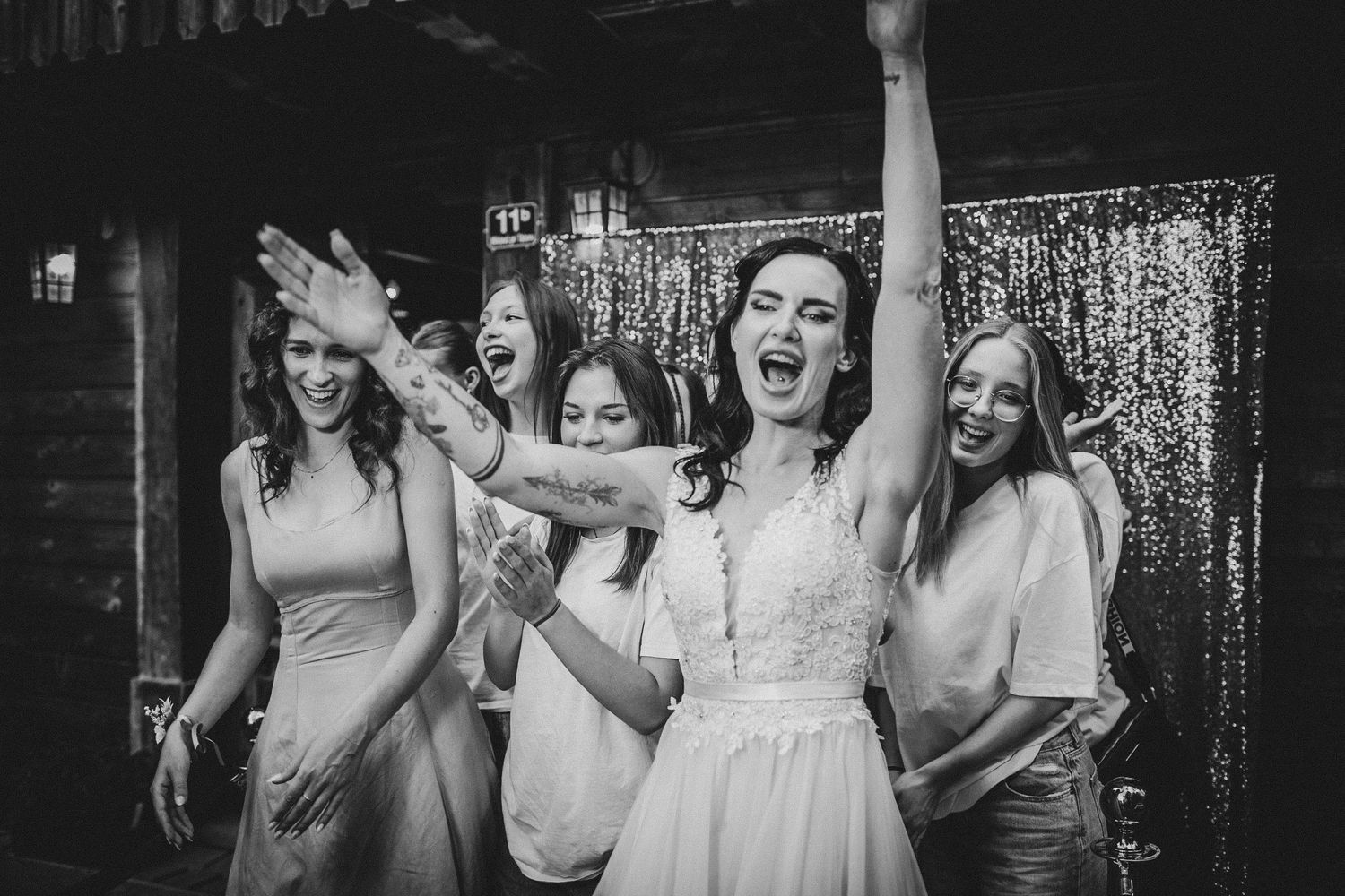 Wedding party celebrates with energetic dancing against a sparkly backdrop.