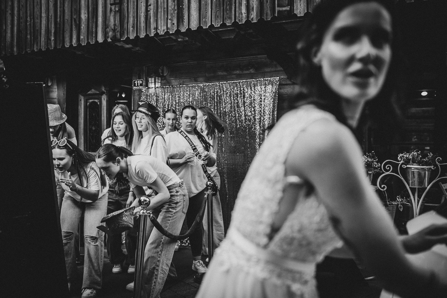 A black and white candid shot of people enjoying a lively dance party at a rustic venue.