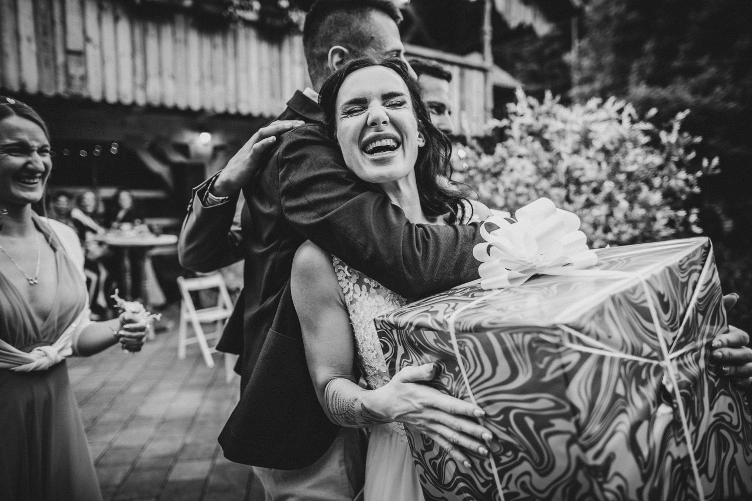 A black and white candid shot capturing an emotional embrace during a celebration.