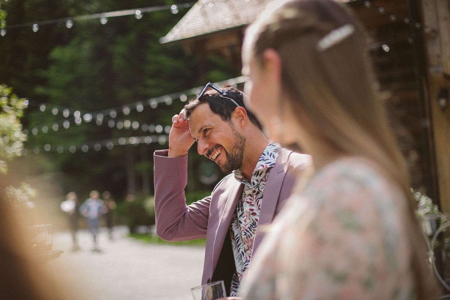 Outdoor summer wedding celebration with string lights and natural decor.
