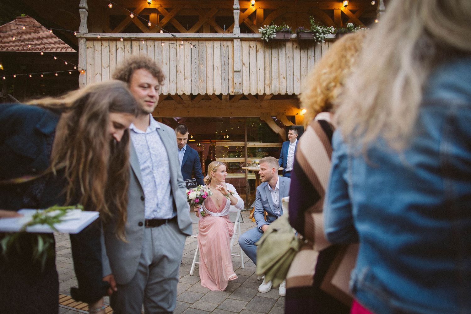 A joyful celebration on an outdoor patio with string lights as guests dance and move animatedly.
