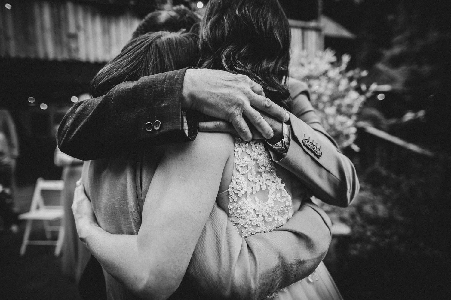 Black and white emotional embrace captured during outdoor celebration.