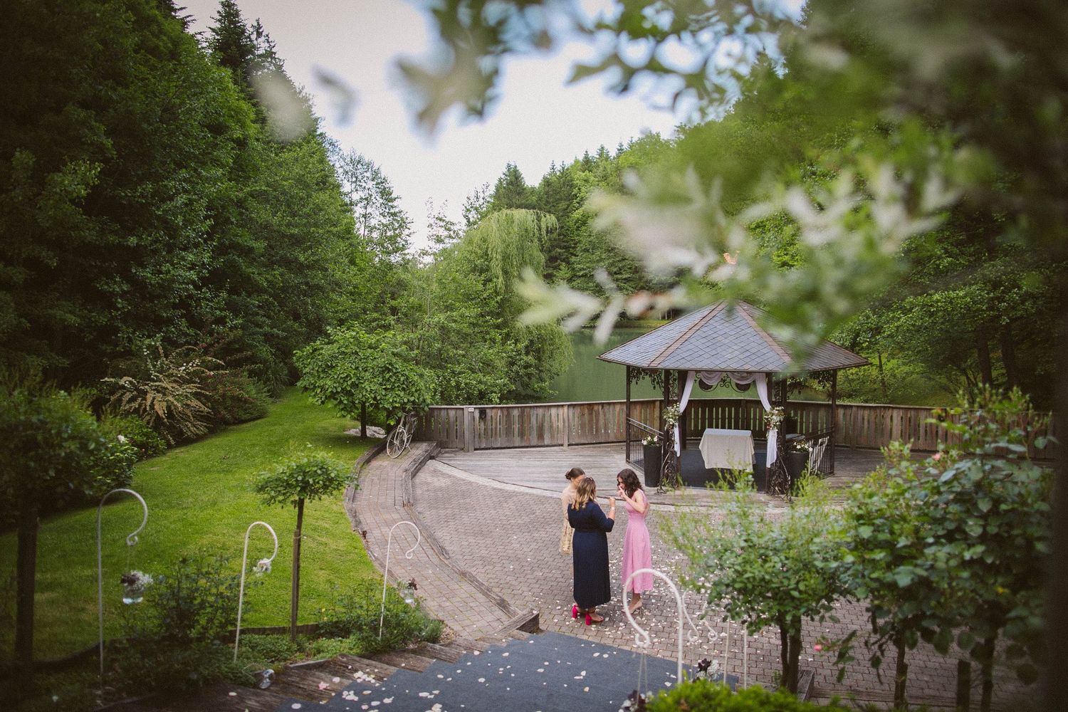 Aerial view of outdoor wedding venue with gazebo nestled among evergreen trees.