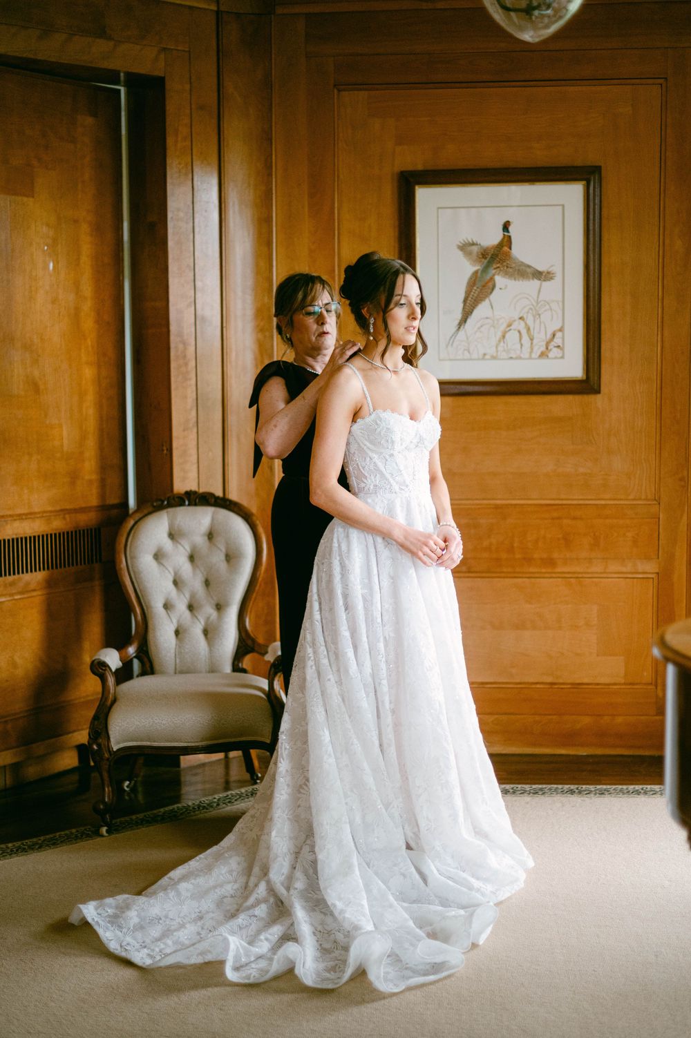 A bride holds a pristine white rose bouquet against her lace wedding dress.
