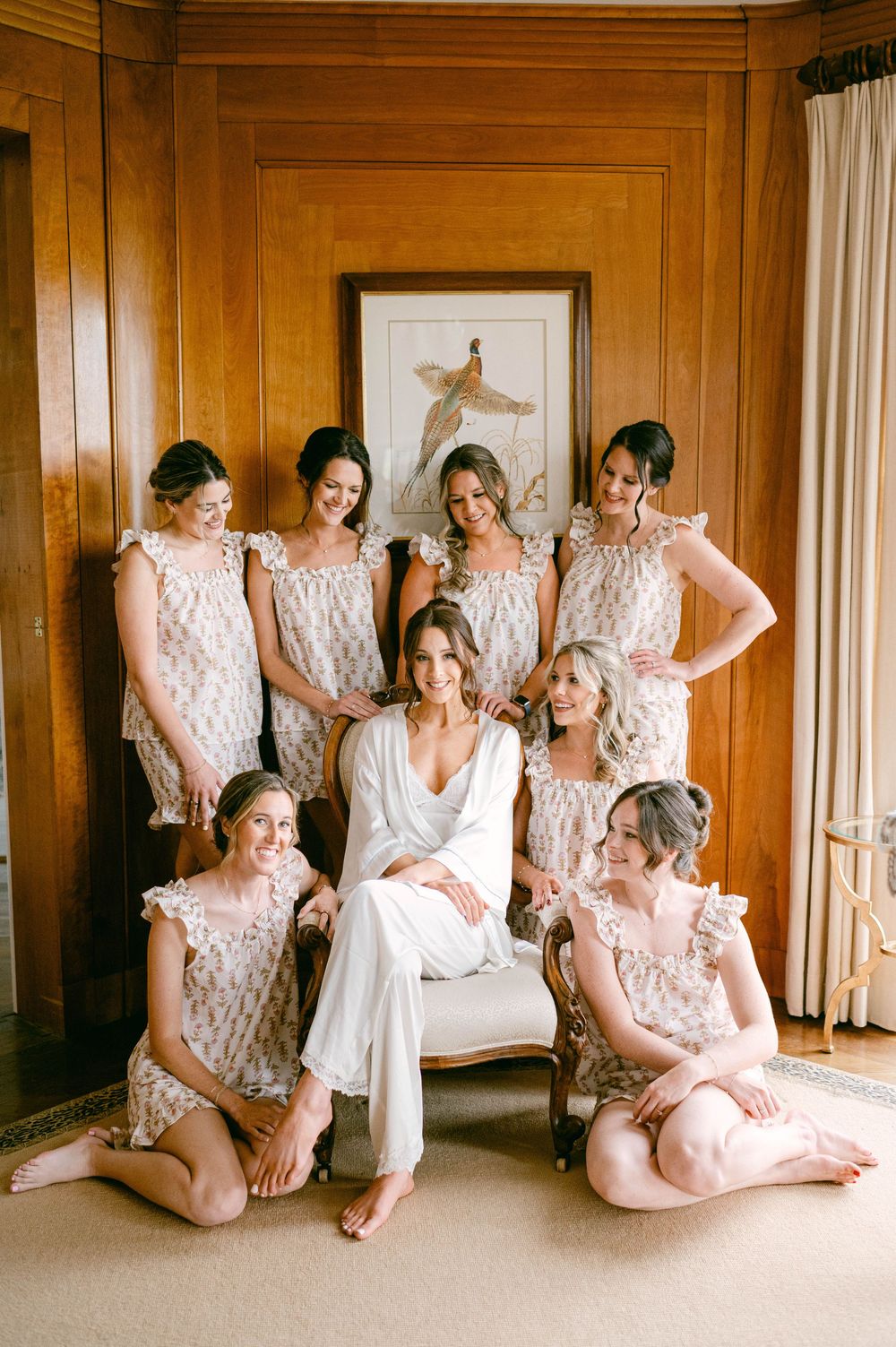 Group wearing light colored robes lounging in an elegant wood-paneled room.