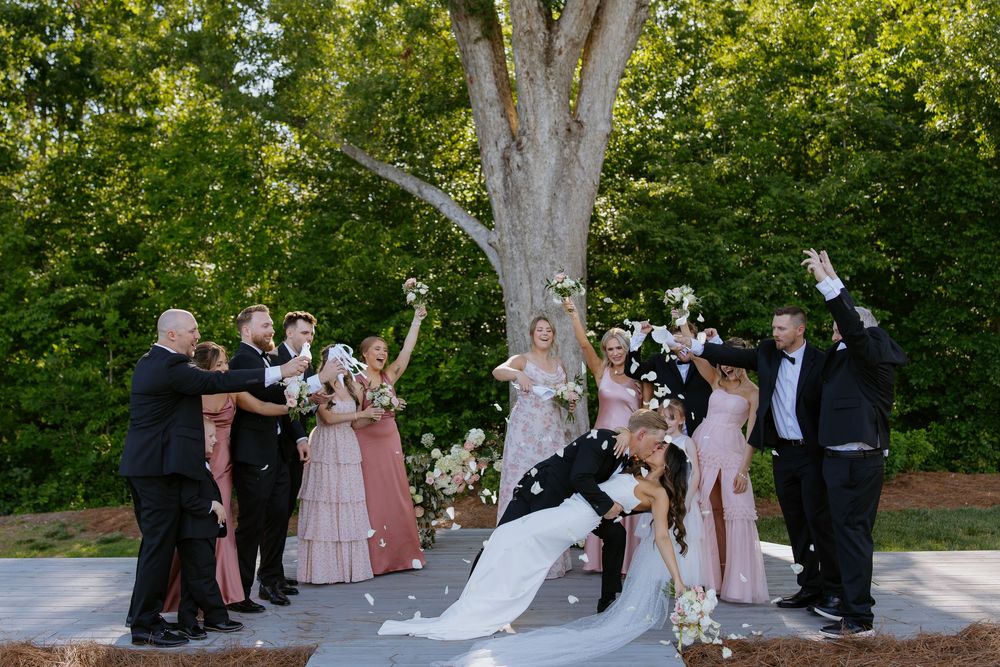 Wedding party celebrates outdoors under trees during a summer ceremony.