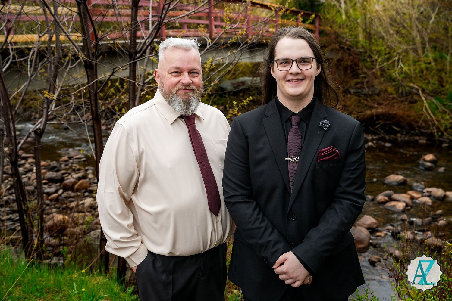 Two people in formal attire standing outside near a stone garden on a cloudy day.