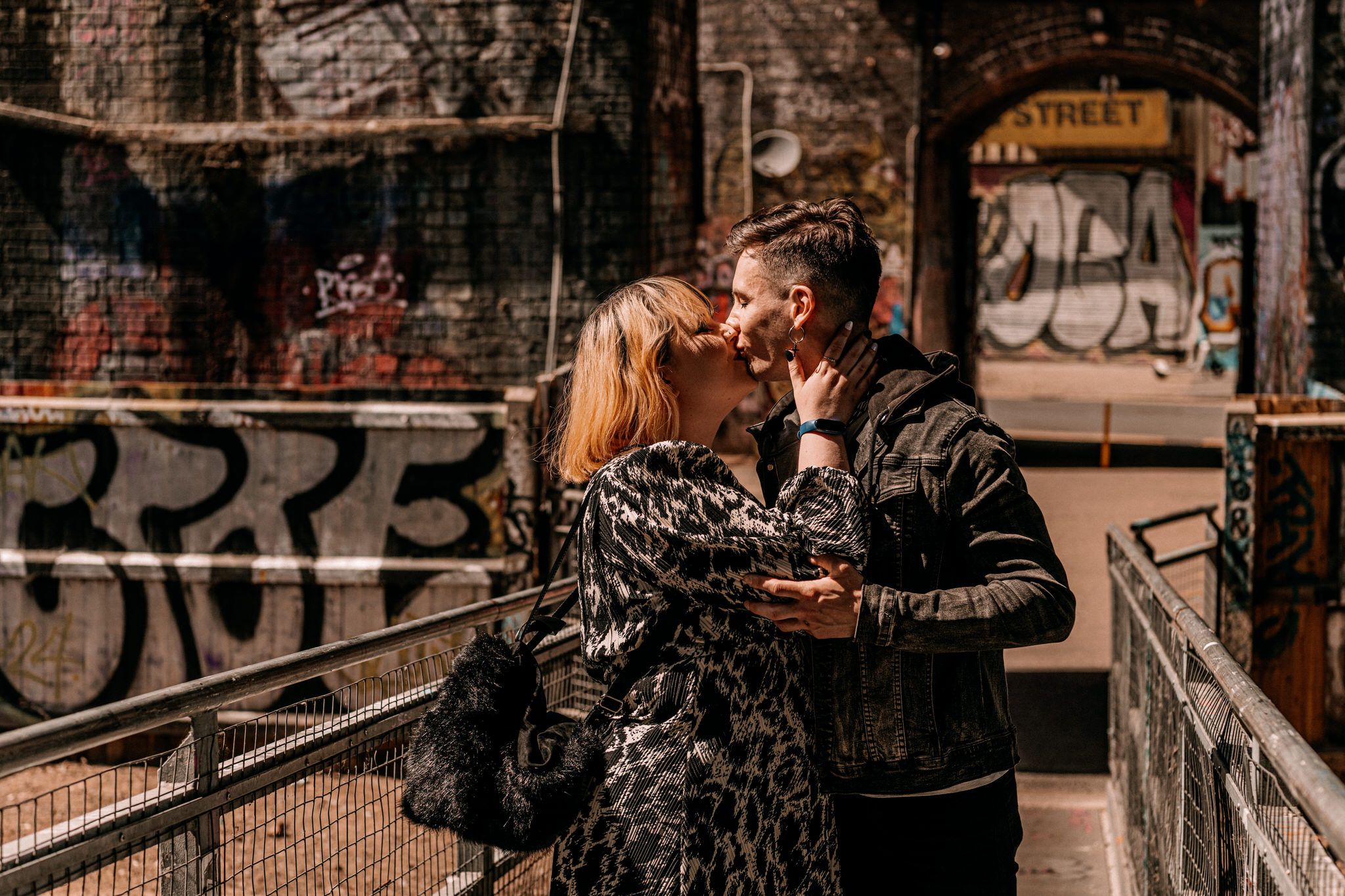 Romantic moment captured in an urban industrial setting with brick walls and graffiti art.