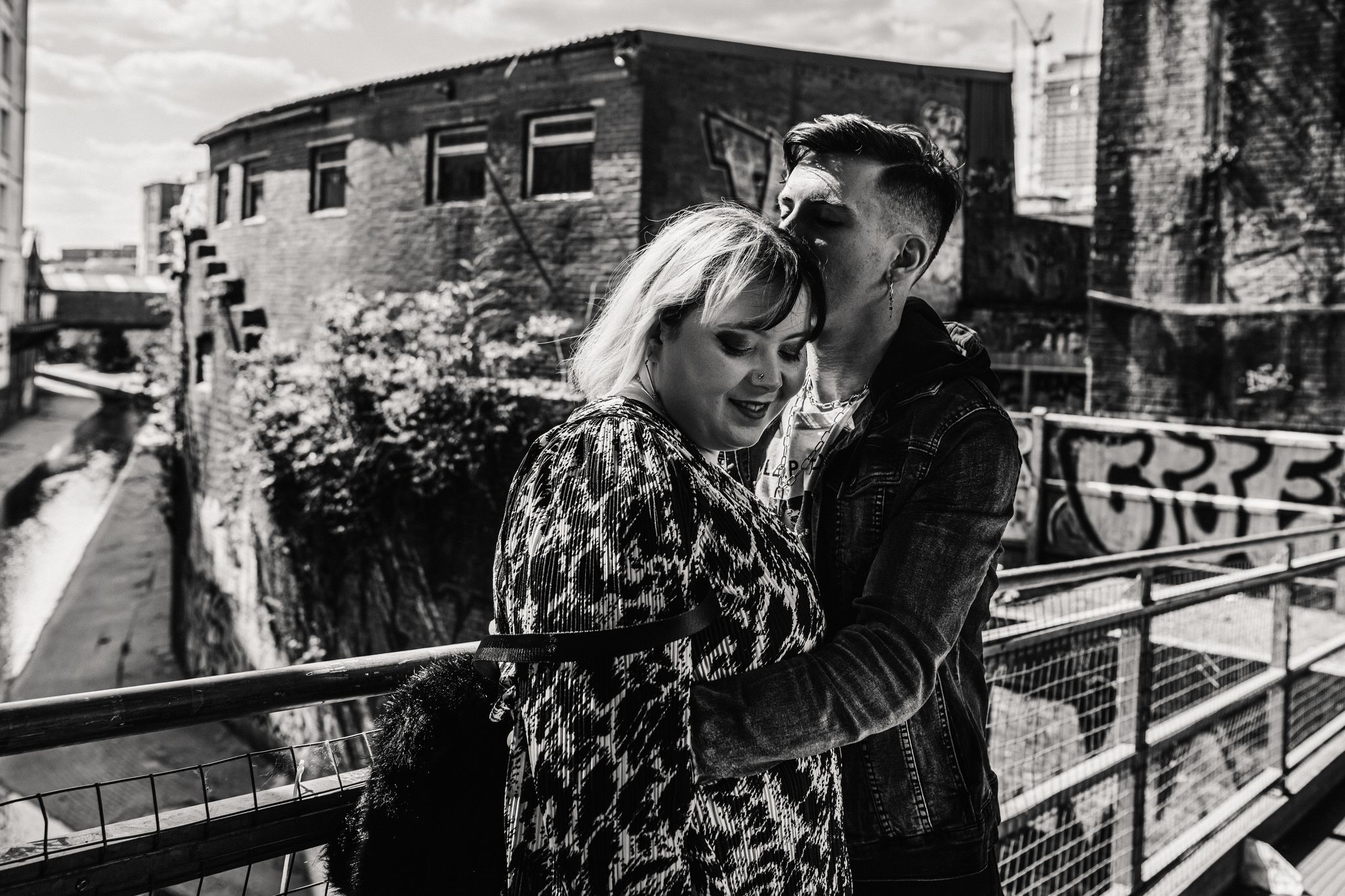 A tender black and white moment shared on an urban balcony with graffiti-covered walls in the background.