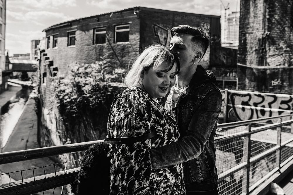 A tender black and white moment shared on an urban balcony with graffiti-covered walls in the background.